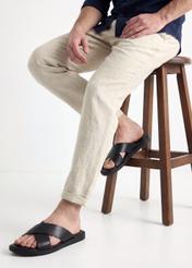 Czarne skórzane klapki męskie BUTYM-0536-99(W26), widok produktu z boku na stopach modela, na jasnym tle.