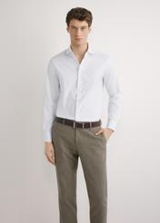 Biała koszula męska z bawełny KOSMT-0358-0A(W26) - widok produktu z przodu, na modelu, na jasnym tle. Widoczna sylwetka do połowy.