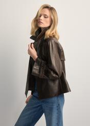 Skórzana kurtka damska w kolorze ciemnobrązowym KURDS-0604-1I(W26), widok produktu z boku na modelce. Widoczna połowa sylwetki.