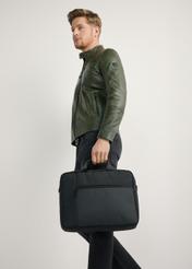 Czarna torba na laptopa TORMN-0401-99(W26) - widok produktu z przodu, trzymanego przez modela w ręku, na jasnym tle. Widoczna połowa sylwetki. 