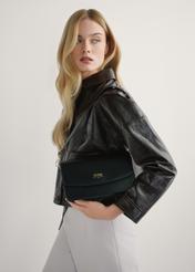 Czarna torebka damska z imitacji skóry TOREC-1081-99(W26), widok produktu w rękach modelki. Widoczna połowa sylwetki.