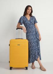 Walizka duża na kółkach WALAB-0040-2B-28(W26), widok produktu od przodu przy modelce, widoczna cała sylwetka.