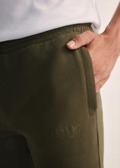 Dresowe spodnie męskie w kolorze khaki SPOMT-0101-55(Z25), zbliżenie na detal produktu na modelu.