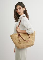 Słomkowa duża torebka damska typu shopper TOREC-1217-1E(W26), widok produktu w rękach modelki. Widoczna połowa sylwetki.