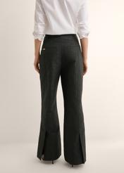 Czarne spodnie wide leg w kwiaty SPODT-0127-99(Z26), widok produktu z tyłu na modelce. Widoczna połowa sylwetki.