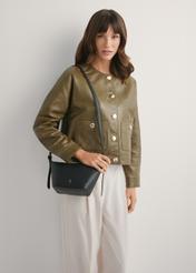 Czarna niewielka torebka ze skóry naturalnej TORES-1267-9I(W26), widok poduktu od przodu na modelce, widoczna połowa sylwetki.