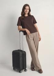 Walizka mała na kółkach  WALAB-0040-99-19(W25), widok produktu skosem przy modelce, widoczna cała sylwetka.