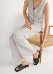 Czarne skórzane klapki damskie BUTYD-1163-99(W26) - widok produktu z przodu, na modelce, na białym tle. Widoczna sylwetka. 