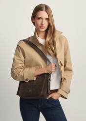 Skórzana torebka damska w kolorze brązowym TORES-1251-1I(W26) - widok produktu po skosie, na modelce, na jasnym tle. Widoczna sylwetka do kolan.