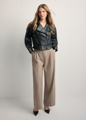 Krótka czarna skórzana kurtka damska KURDS-0607-99(W26) - widok produktu z przodu na modelce, na jasnym tle. Widoczna cała sylwetka.