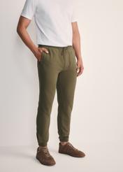 Dresowe spodnie męskie w kolorze khaki SPOMT-0101-55(Z25), widok produktu z przodu na modelu. Widoczna połowa sylwetki.