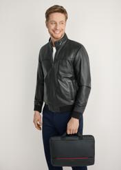 Czarna torba na laptopa TORMN-0398-9J(W26) - widok produktu z przodu, trzymanego przez modela w ręku, na jasnym tle. Widoczna sylwetka do kolan. 