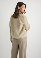 Krótkie beżowe futro damskie FUTDP-0079-1A(W26), widok produktu z tyłu na modelce. Widoczna połowa sylwetki.