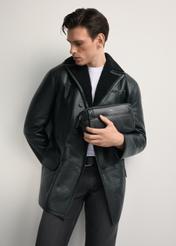 Skórzana kosmetyczka męska z logo TORMS-0298A-99(Z25) - widok produktu po skosie, trzymanego przez modela w ręku, na białym tle. Widoczna sylwetka do kolan.