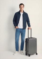 Walizka średnia na kółkach WALAB-0073-9C-24(W26), widok produktu skosem obok sylwetki modela.