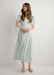 Długa sukienka w kwiaty w kolorze szałwiowym SUKDT-0191-8P(W26), widok produktu z przodu na modelce. Widoczna cała sylwetka.