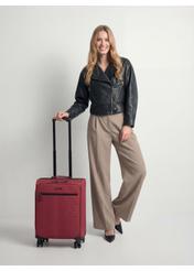 Walizka średnia na kółkach WALNY-0045-4B-24(W26), widok produktu z przodu obok sylwetki modelki.