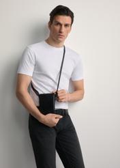 Czarna skórzana saszetka męska TORMS-0420A-99(Z25) - widok produktu z przodu, trzymanego przez modela w ręku. Widoczna połowa sylwetki. 