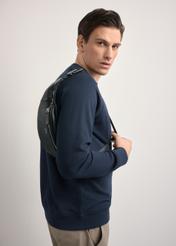 Czarna skórzana nerka męska z logo TORMS-0295A-99(Z25) - widok produktu z boku, na modelu, na białym tle. Widoczna sylwetka do kolan.