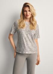 Srebrna cekinowa bluzka damska BLUDT-0199-92(Z25), widok produktu przodem na modelce, widoczna połowa sylwetki.