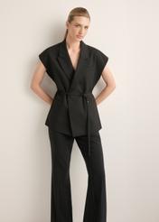 Czarna kamizelka garniturowa damska oversize KAMDT-0039-99(Z26), widok produktu z przodu na modelce. Widoczna cała sylwetka.