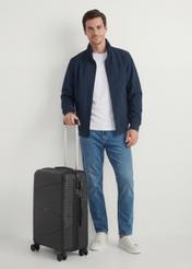 Walizka średnia na kółkach WALPP-0021-99-24(W25), widok produktu skosem przy modelu, widoczna cała modelka.