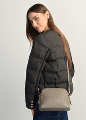 Jasnobrązowa torebka damska z monogramem TOREC-1180-1K(W26), widok produktu na ramieniu modelki. Widoczna połowa sylwetki.