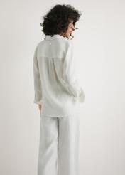 Biała koszula damska z lnu KOSDT-0163A-0B(W26) - widok produktu z tyłu, na modelce, na jasnym tle. Widoczna połowa sylwetki. 