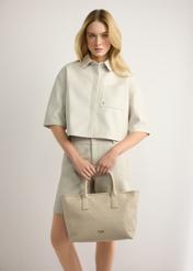 Kremowa torebka damska z plecionką TOREC-1212-0B(W26) - widok produktu z przodu, trzymanego przez modelkę w ręku, na jasnym tle