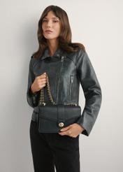 Czarna torebka listonoszka damska TOREC-1137-99(W26), widok produktu w rękach modelki. Widoczna połowa sylwetki.