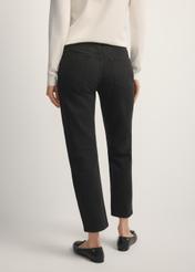 Czarne spodnie jeansowe damskie JEADT-0011-99(W26), widok produktu z tyłu na modelce. Widoczna połowa sylwetki.