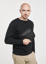Czarna kosmetyczka męska TORMS-0267C-99(Z25), zbliżenie na produkt w dłoni modela. Widoczna połowa sylwetki.