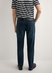 Ciemnoniebieskie jeansowe spodnie męskie JEAMT-0022-7C(W26), widok produktu z tyłu na modelu. Widoczna połowa sylwetki.