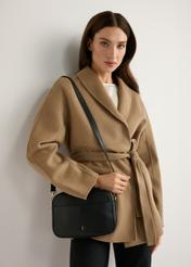 Czarna mała torebka damska skórzana TORES-1284-9I(W26) - widok produktu z przodu, na modelce, na jasnym tle. Widoczna sylwetka do połowy. 