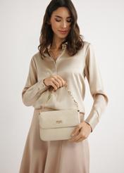 Kremowa pleciona torebka damska TOREC-0767-0P(W26) - widok produktu trzymanego przez modelkę, w ręku na jasnym tle. Widoczna sylwetka do połowy. 