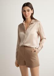 Damskie eleganckie szorty w kolorze camelu SZODT-0018-1D(W26), widok produktu z przodu na modelce. Widoczna połowa sylwetki.