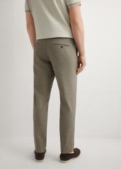 Ciemnobrązowe spodnie garniturowe męskie SPOMT-0098-1I(W26), widok produktu z tyłu na modelu. Widoczna połowa sylwetki.