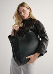 Czarna skórzana torebka shopper damska TORES-1208-9I(W26) - widok produktu, trzymanego przez modelkę w ręku, na jasnym tle. Widoczna połowa sylwetki.