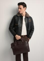 Brązowa skórzana torba męska TORMS-0460-89(Z25) - widok produktu z przodu, trzymanego przez modela w ręku. Widoczna połowa sylwetki.