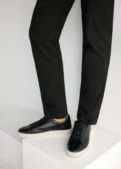 Czarne skórzane sneakersy męskie BUTYM-0486-99(W26), widok produktu od boku na modelu, widoczna połowa sylwetki.