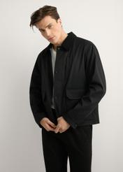 Czarna przejściowa kurtka męska KURMT-0419-99(W26) - widok produktu z przodu, na modelu, na jasnym tle. Widoczna sylwetka do kolan.