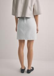 Kremowa denimowa spódnica mini SPCDT-0126-0B(W26), widok produktu z tyłu na modelce. Widoczna połowa sylwetki.