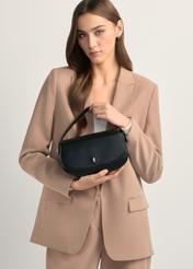 Mała czarna torebka listonoszka damska TOREC-1185-99(W26), widok produktu w rękach modelki. Widoczna połowa sylwetki.