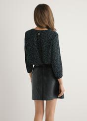 Bluzka damska w kropki BLUDT-0172A-9P(W26) - widok produktu z tyłu, na modelce, na jasnym tle. Widoczna połowa sylwetki. 