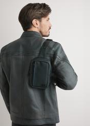 Czarna męska saszetka na ramię TORMN-0393-9J(W26) - widok produktu z przodu, na modelu, stojącym tyłem, na jasnym tle. Widoczna połowa sylwetki.