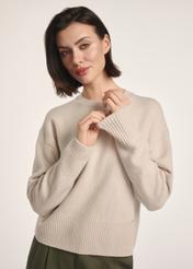 Beżowy sweter damski SWEDT-0242-80(Z25), widok produktu z przodu na modelce. Widoczna połowa sylwetki.