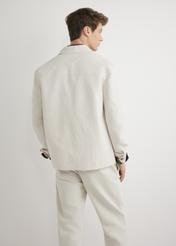 Jasnobeżowa lniana kurtka męska KURMT-0420-1A(W26) - widok produktu z tyłu, na modelu, na jasnym tle. Widoczna połowa sylwetki. 