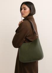Zielona torebka damska hobo TOREC-1257-8B(Z26), widok skosu produktu, na modelce, na jasnym tle. Widoczna połowa sylwetki. 