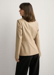 Beżowa skórzana marynarka damska KURDS-0445-1B(W26), widok produktu z tyłu na modelce. Widoczna połowa sylwetki.