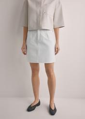 Kremowa denimowa spódnica mini SPCDT-0126-0B(W26), widok produktu z przodu na modelce. Widoczna połowa sylwetki.